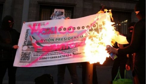 Feministas encapuchadas queman boleto de rifa de avion presidencial afuera de Palacio Nacional