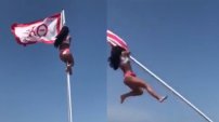 Chica spring breaker se sube al asta de una bandera y cae como bulto en la playa
